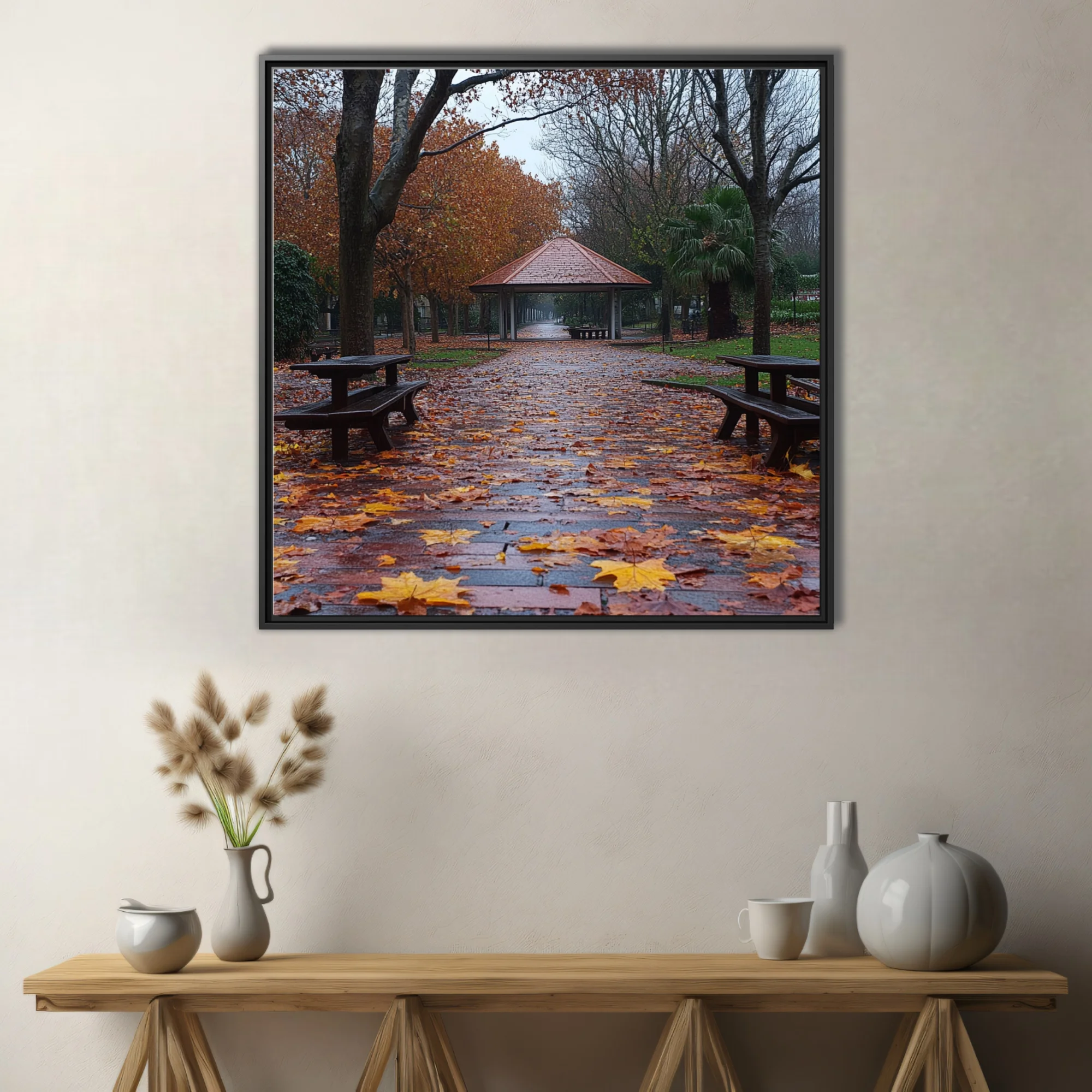 Rainy autumn park path with fallen leaves, picnic tables, and a gazebo in muted amber and grey