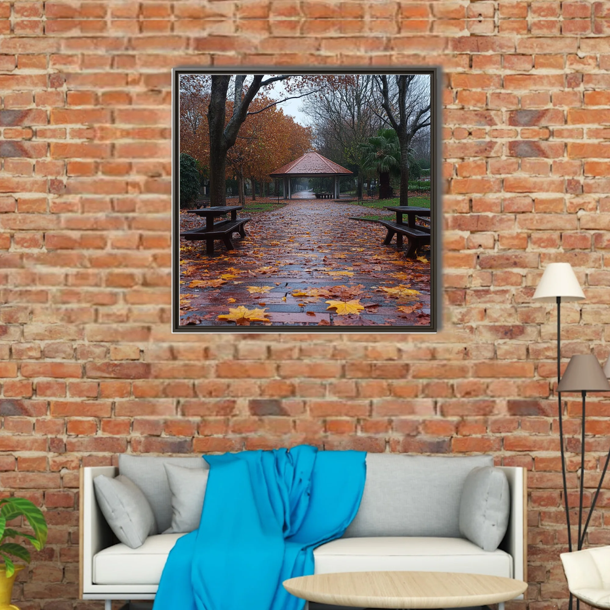 Rainy autumn park path with fallen leaves, picnic tables, and a gazebo in muted amber and grey