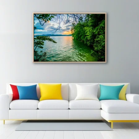 Lush forested lake at golden sunset with misty mountain backdrop and calm water
