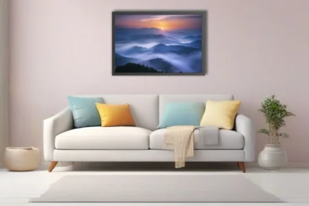 Misty mountain landscape at sunrise with layered blue fog and warm horizon glow