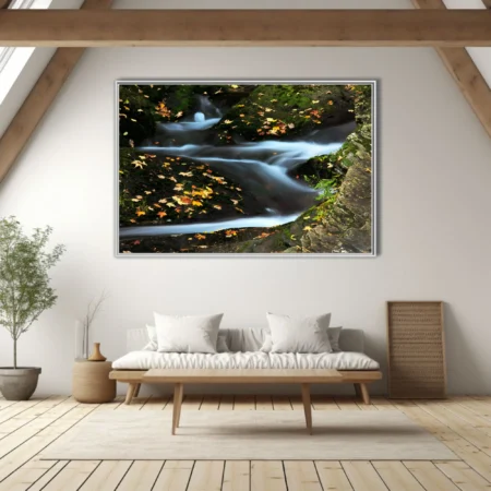 Long-exposure mountain stream with autumn leaves on mossy rocks, blue-white silky water