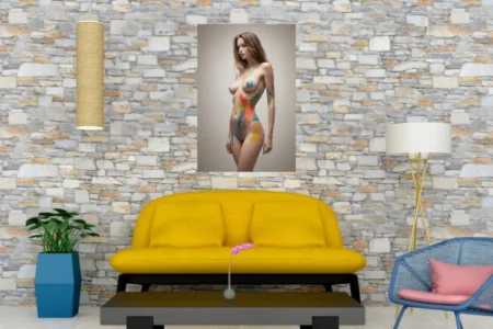 Nude woman with bursts of saturated body paint across her skin, standing against a neutral backdrop